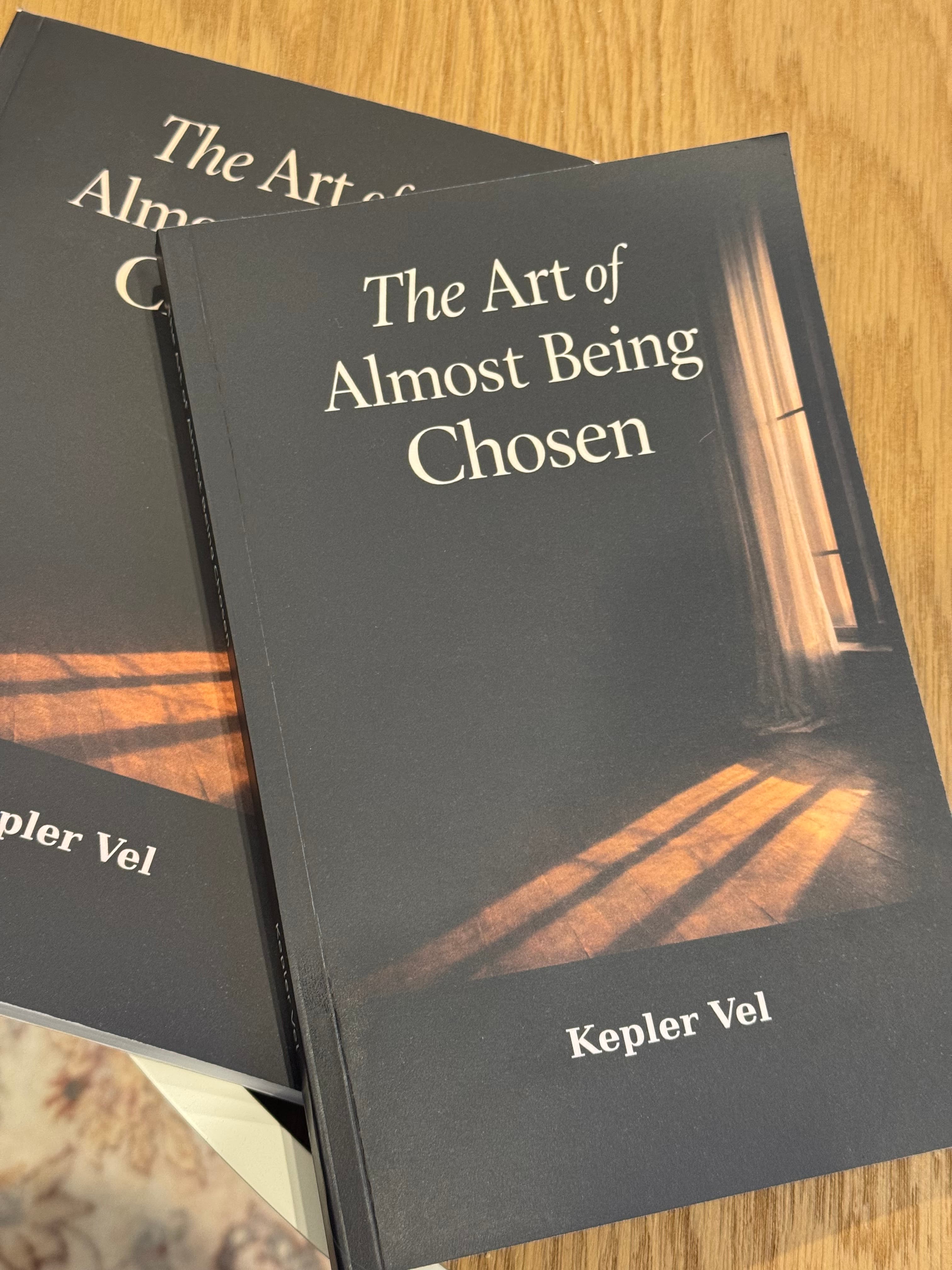 Two copies of the book flat on a warm wooden table