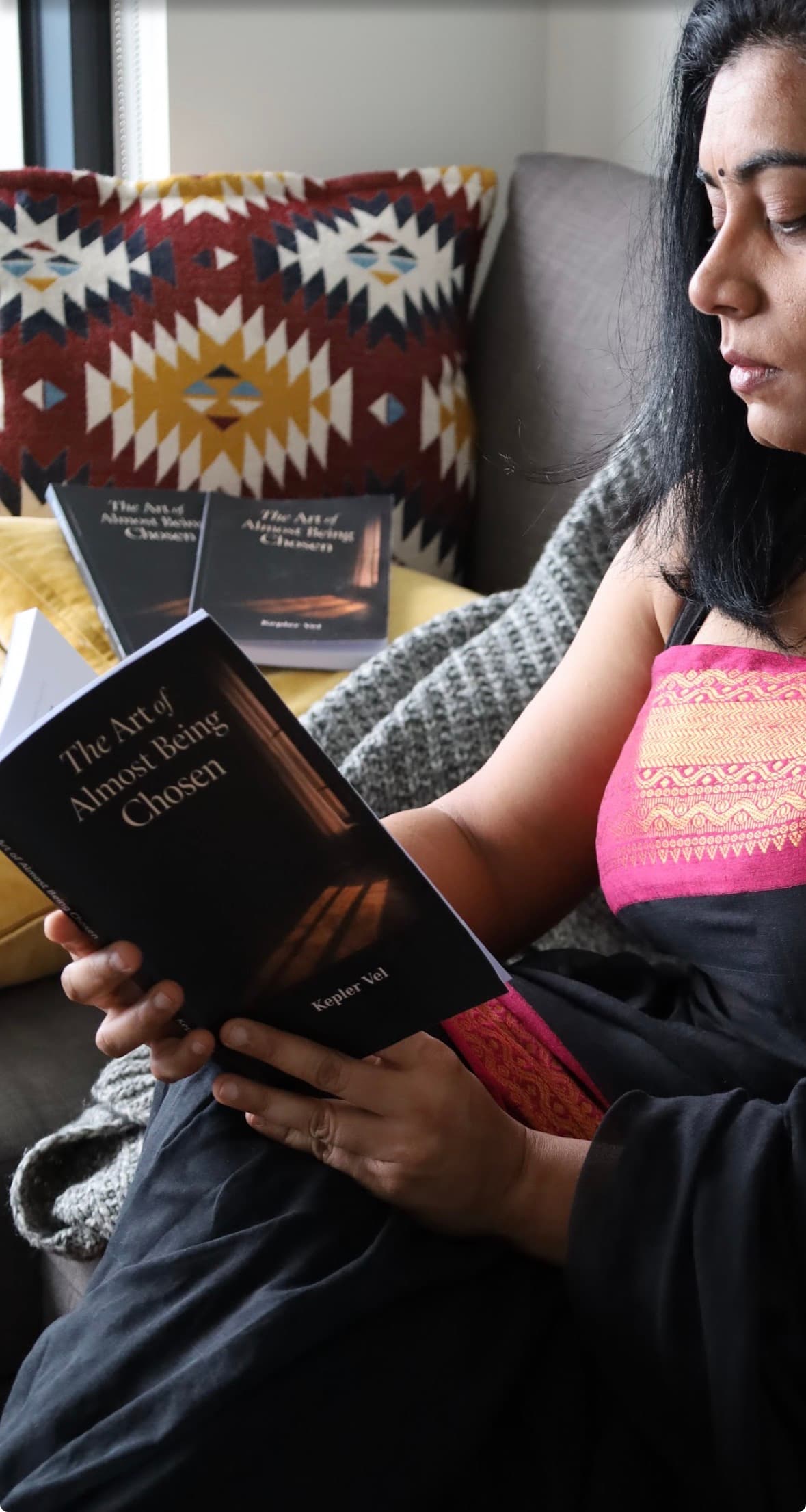 Author reading on couch with multiple copies of the book
